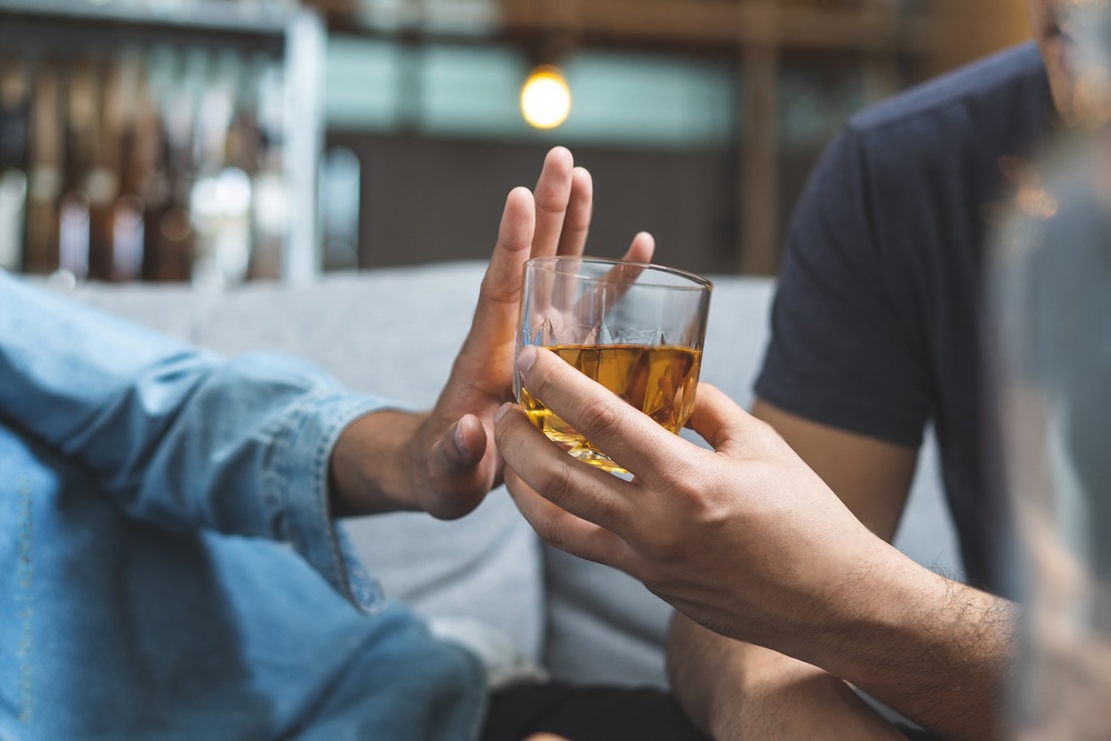 Person bietet einer anderen Alkohol an, aber die Person lehnt den Alkohol ab